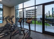 Thumbnail 28 of 37 - cardio bikes in the gym of a building with a view of theenced in patio