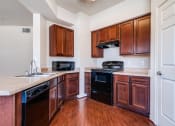 Thumbnail 2 of 30 - an empty kitchen with wooden cabinets and a black stove and oven