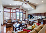 Thumbnail 13 of 30 - a large living room with a kitchen and a ceiling fan