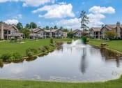 Thumbnail 27 of 30 - a pond with a fountain in the middle of a green field with houses