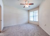 Thumbnail 8 of 30 - an empty living room with a ceiling fan and a window