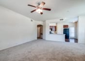 Thumbnail 3 of 30 - an empty living room with a ceiling fan and a kitchen