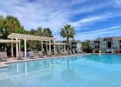 Thumbnail 19 of 26 - A large swimming pool with a white pergola and lounge chairs.