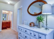 Thumbnail 12 of 26 - A white dresser with a round mirror above it and a potted plant on top.