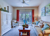 Thumbnail 16 of 26 - A living room with a couch, a chair, a table, and a ceiling fan.