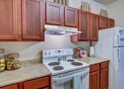 Thumbnail 11 of 26 - A kitchen with a white stove and a white refrigerator.