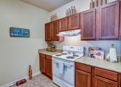Thumbnail 10 of 26 - A kitchen with a white stove and wooden cabinets.
