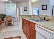 Thumbnail 9 of 26 - A kitchen with a sink, dishwasher, and a table with chairs.