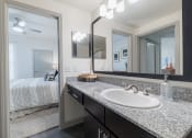 Thumbnail 12 of 36 - a bathroom with a sink and mirrors and a bedroom with a bed