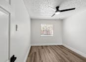 Thumbnail 28 of 38 - A room with a ceiling fan and wooden flooring.