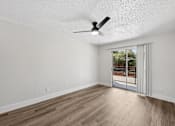 Thumbnail 25 of 38 - A room with a ceiling fan and sliding glass doors leading to a balcony.
