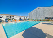 Thumbnail 35 of 40 - A large swimming pool with a blue tinted water and a white building in the background.