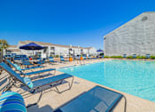 Thumbnail 33 of 40 - A pool with sun loungers and a building in the background.