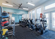 Thumbnail 25 of 40 - A gym with a variety of equipment including treadmills, weights, and a fan.