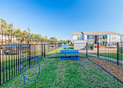 Thumbnail 31 of 40 - A playground with a blue swing set and a metal fence.