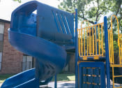 Thumbnail 15 of 16 - a playground with a blue slide and a yellow slide