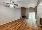 Thumbnail 7 of 16 - an empty living room with wood flooring and a ceiling fan