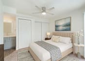 Thumbnail 4 of 19 - A bedroom with a large bed, a ceiling fan, and a painting on the wall.