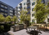 Thumbnail 7 of 24 - an outdoor patio with a picnic table in front of an apartment building