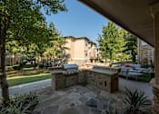 Thumbnail 17 of 39 - Stone patio with a grill at Woodbridge Villas Apartments, Texas