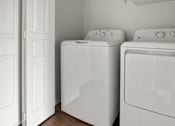 Thumbnail 8 of 21 - Two white front loading washing machines in a laundry room.