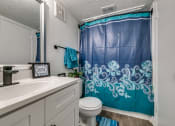 Thumbnail 19 of 36 - a bathroom with a blue shower curtain and a white sink and toilet