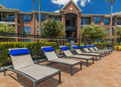 Thumbnail 52 of 54 - a row of chaise lounges on a brick patio in front of a brick building