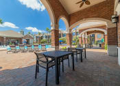 Thumbnail 29 of 54 - a patio with tables and chairs and a pool in the background