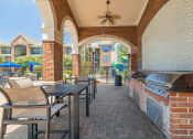 Thumbnail 31 of 54 - a covered patio with a grill and tables and chairs