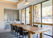 Thumbnail 7 of 25 - a dining area with a wooden table and chairs and a kitchen with large windows