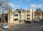 Thumbnail 11 of 23 - A parking lot with cars and apartment buildings in the background.