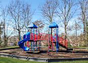 Thumbnail 17 of 19 - A playground with a red and blue slide and a blue roofed structure.