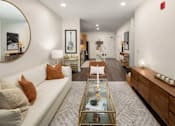 Thumbnail 1 of 21 - A living room with a white couch, a coffee table, and a guitar picture frame on the wall.