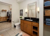 Thumbnail 6 of 21 - A bathroom with a toilet, sink, and mirror.