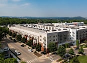 Thumbnail 20 of 21 - A large white building with a parking lot in front of it.