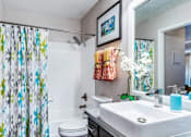 Thumbnail 10 of 17 - A bathroom with a white toilet, a sink, and a shower curtain.