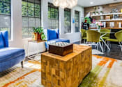 Thumbnail 2 of 17 - A living room with a blue couch, a wooden coffee table, and a rug with a geometric pattern.