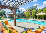 Thumbnail 12 of 17 - A pool with orange sun loungers and a wooden pergola.
