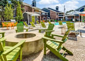 Thumbnail 16 of 17 - A sunny day at a poolside with green chairs and a fire pit.