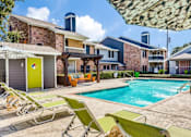 Thumbnail 15 of 17 - A pool area with sun loungers and a building in the background.