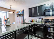 Thumbnail 7 of 17 - A kitchen with black cabinets and appliances, a window with blinds, and a hanging light fixture.