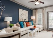 Thumbnail 6 of 24 - A living room with a white couch, a side table, and a ceiling fan.