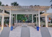 Thumbnail 22 of 26 - A patio with a white pergola and grey tiles.