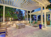 Thumbnail 23 of 26 - A patio with a white pergola and a stone wall.