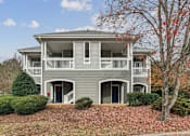 Thumbnail 34 of 45 - A grey two-story house with a balcony and a tree with red leaves in front.