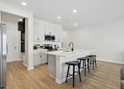 Thumbnail 13 of 37 - A kitchen with white cabinets and a white island with black stools.