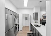 Thumbnail 18 of 45 - A modern kitchen with a stainless steel refrigerator and a sink.