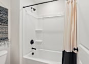 Thumbnail 31 of 37 - A white bathroom with a black and white bathtub.