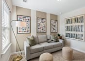 Thumbnail 25 of 37 - A living room with a grey couch, a floor lamp, and pictures on the wall.