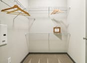 Thumbnail 16 of 19 - a white closet with two hangers and a clock on the wall